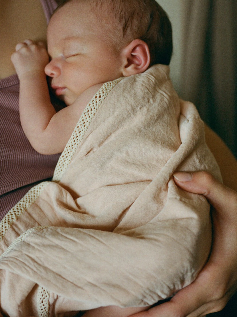 A sleeping newborn wrapped in a cream blanket