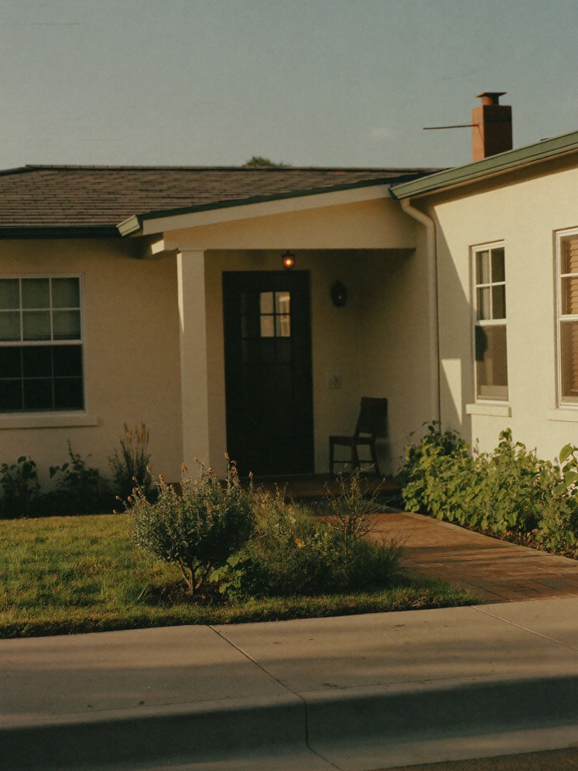 A cream bungalow with a dark front door in late afternoon light